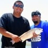 Father and Son, Israel Carbajae and Israel Jr display their catch of the day, a nice slot red caught on finger mullet.