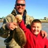 Dad helps son Landon Wilson of Bullard Elementary School heft his first keeper flounder caught on a Miss Nancy mud minnow