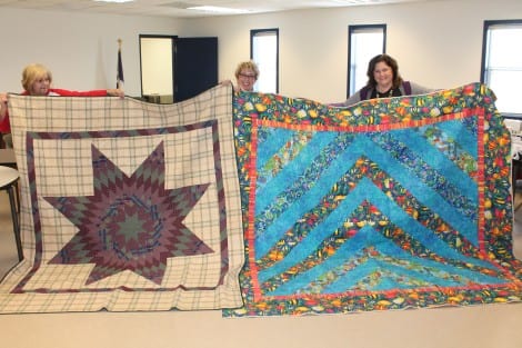 The Crystal Beach Bees presented two handmade quilts to the Lone Survivor Retreat Facility. The octogram quilt was donated by Dot Collins with the Golden Triangle Quilt Guild, and Brenda McDonald, with the Crystal Beach Bees, made the marine-theme quilt. Pictured are Brenda McDonald, Linda Hollier and Denise Lange.