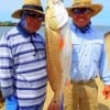 Dad and son anglers Rolly and Jonry Edralin of Sugarland TX heft this 30inch tagger bull red caught on a finger mullet