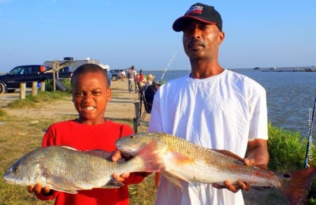 Father and son fishing team Kirk Carter JR along with HISD Student Kirk Carter III show off part of their fishing creel of reds, drum, croaker, and trout the took on shrimp