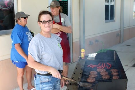 Fire department member Tessa Tedder flipping burgers and roasting dogs. 